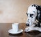 Dog dalmatian sitting at the table with a cup of coffee cappuccino