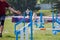 Dog with handler vaulting hurdle in agility trial