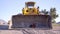 Dog in an orange construction vest and helmet sitting in yellow bulldozer