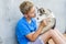 Dog owner petting and scratching his pet on a concrete background