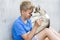 Dog owner petting and scratching his pet on a concrete background