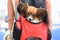 A dog of the Papillon breed sits in a red backpack behind the mistress