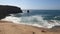 Dog playing on the beach of the wavy sea with coastline rocks in Peniche, Portugal