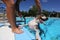 A dog plays with his owner at the edge of a swimming pool