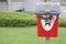 Dog poo waste only sign on red bin over flowing too many doggy bags falling out in public park encouraging owners pick up afterwa