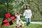 Dog scares kid. Positive female child and grandmother running with red and black colored kite in hands outdoors