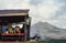 A dog sits near a make-shift hut exhibiting tropical fruit for sale set against Agung volcano of Bali. Retro 1993 film capture