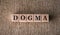 DOGMA word written on wooden blocks on a brown background