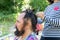 doing haircut for men with long black hair. girl braids a pigtail to a middle-aged bearded man