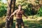 Doing workout. Handsome shirtless man with muscular body type is in the forest at daytime