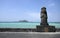 Dol hareubang statue in front of a turquoise sea, Jeju Island, South Korea.