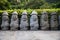 Dol Hareubang statues in a row in green forest, Seogwipo, Jeju Island, South Korea