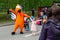 The doll of big growth in the form of an orange bird, the symbol of the Dodo pizzeria-pizza, is photographed with children at the