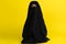 doll in a black robe with a closed face on a yellow background