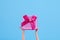 Doll hands holding pink gift box on light blue background