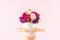 Doll holding spring flowers in cracked eggshell against pastel pink background. Easter minimal concept. Creative Happy Easter or