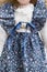 Doll in old textile knitted blue dress with tender floral print