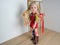 Doll with pigtails in smart clothes, in a red sundress and boots, concept children`s toy, doll fashion, hobby, for girls, happy