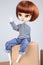 Doll red hairs in jeans sit on brown carton box in white background pretty fashion girl