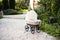 Doll\'s pram. Vintage doll stroller placed on the stone walkway, alley in a beautiful garden