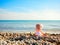 Doll sitting on beach and pointing to the sea