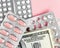 Dollars banknote and pills in blister on a pink background, rising prices of healthcare system. Vaccine and antibiotic for
