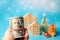 Dollars in hand on background wooden houses, christmas tree and gifts. Christmas and new year preparation concept. Discounts,