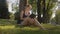 Dolly shot of beautiful young woman sitting under the tree and reading a book