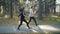 Dolly shot of cheerful friends woman and man running and jumping in park doing sports and smiling together. Good mood