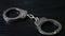 Dolly shot of handcuffs on dark background