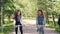 Dolly shot of happy young women cheerful students riding bicycles in city park, talking and laughing enjoying weekends