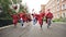 Dolly shot of joyful graduating students running with diplomas waving mortar-boards and laughing. Higher education