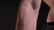 Dolly shot from top to bottom of male muscular arm and fist on black background.