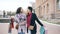 Dolly shot of two attractive mixed race women dancing and have fun while walking down the street with shopping bags