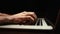 Dolly-in shot of young man working typing on keyboard laptop computer at dark room, close-up.