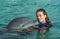 Dolphin kiss young woman in blue water. Smiling woman swimming with dolphin. Blue ocean water background