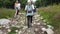 Dombay, Russia 26 July 2020: Group of people go hiking in wooded and hilly area. Rear view of woman engaged in nordic