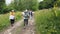 Dombay, Russia 26 July 2020: Group of people go hiking in wooded and hilly area. Rear view of woman engaged in nordic