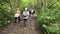 Dombay, Russia 26 July 2020: Group of people go hiking in wooded and hilly area. Rear view of woman engaged in nordic