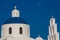 Dome and bell tower of the Church of Panagia Platsani and the moon located in Oia city at Santorini Island in a beautiful early