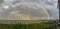 Dome shaped rainbow over ocean and beach and pier