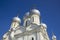 Domes of a white orthodox church with gold crosses against the blue clear sky, bottom view