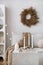 Domestic and cozy christmas living room interior with corduroy sofa, white shelf, candlestick with candle, christmas wearth,