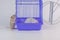 Domestic life and monotony concept. Routine. White rat on a white background in a purple cage with a wheel. Symbol of 2020