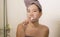 Domestic lifestyle portrait of young happy and beautiful Asian Chinese woman brushing her teeth wearing head towel wrap at