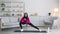 Domestic pilates. Young active middle eastern woman wearing sport suit and traditional headscarf stretching at home