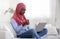 Domestic Relax. Black Muslim Lady Using Laptop And Drinking Coffee At Home
