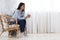 Domestic Relax. Smiling Korean Lady Resting In Armchair With Coffee At Home