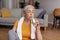 Domestic sports and hydration. Senior woman drinking fresh water from glass, resting after exercising at home