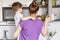 Domestic work, children and motherhood concept. Busy housewife tries to find necessary products in shelf of kitchen, holds small k